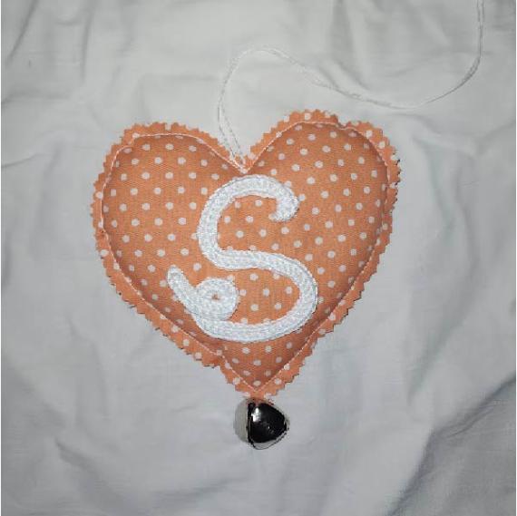 cuore imbottito di stoffa con base arancione a pois bianchi con S di cordoncino e sonaglio